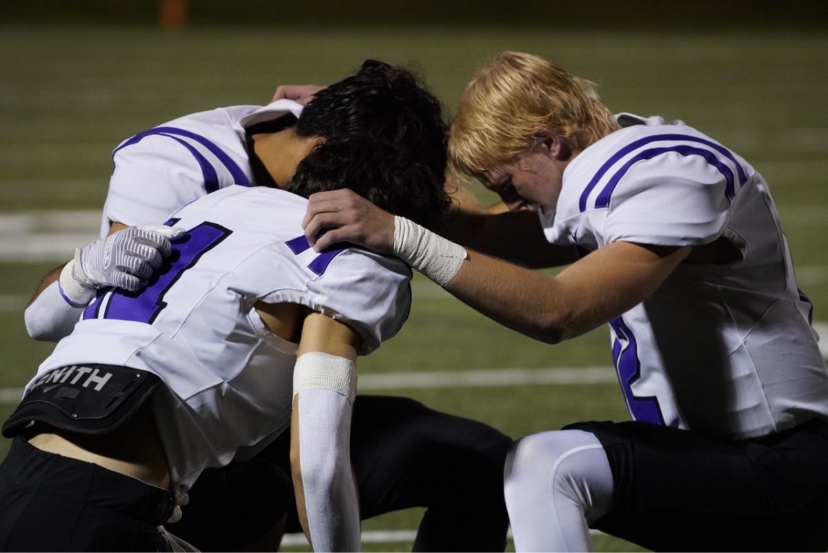 Quarterback Eli Abramson prays with his fellow teammates